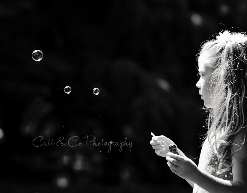 Little girl blowing bubbles in the sun, portrait